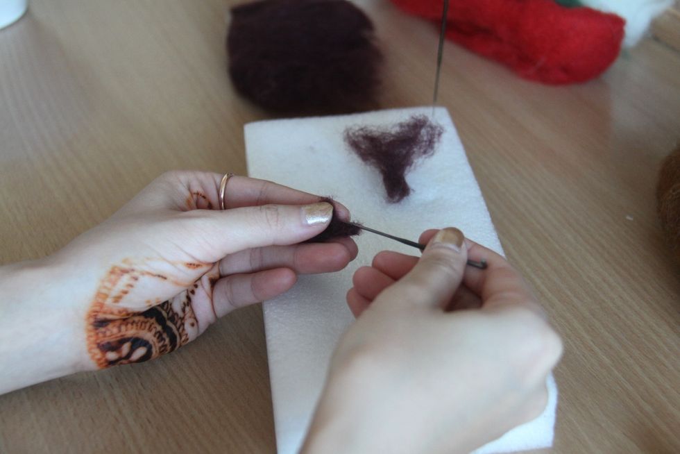 Use a equal parts of dark brown wool to form 2 horns. Leave the end untouched.