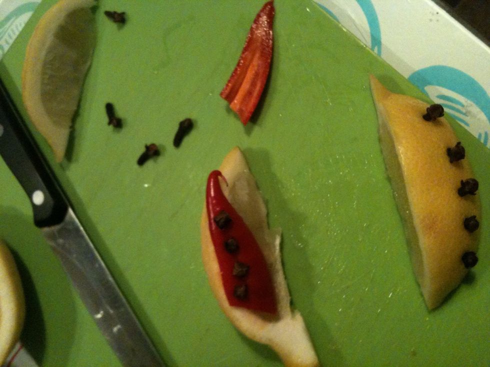 Use a few cloves to attach about 1/4 chilli to a 2nd lemon slice, I find it sticks best if you first push cloves through chilli then into white pith of lemon