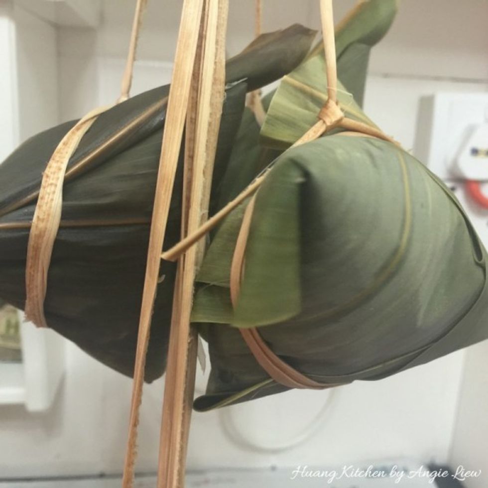 Use a grass strand to tie the rice dumpling. Wrap the dumpling with the grass strand twice, each time with an easy knot to ensure no loose ends. And we're ready to cook them!