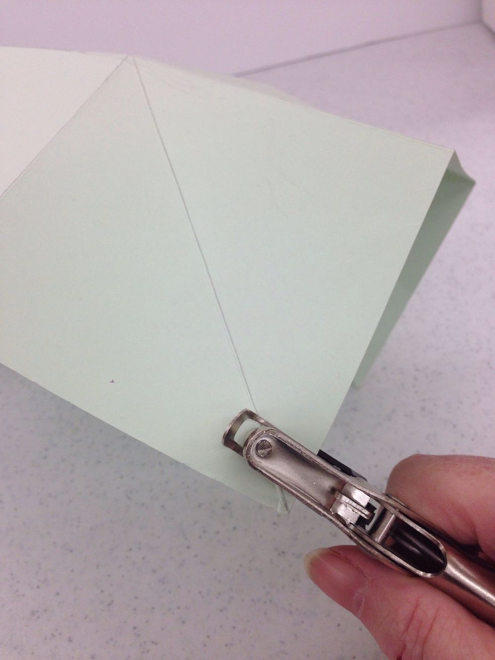 Use a hole punch to punch a hole about half an inch from each corner.