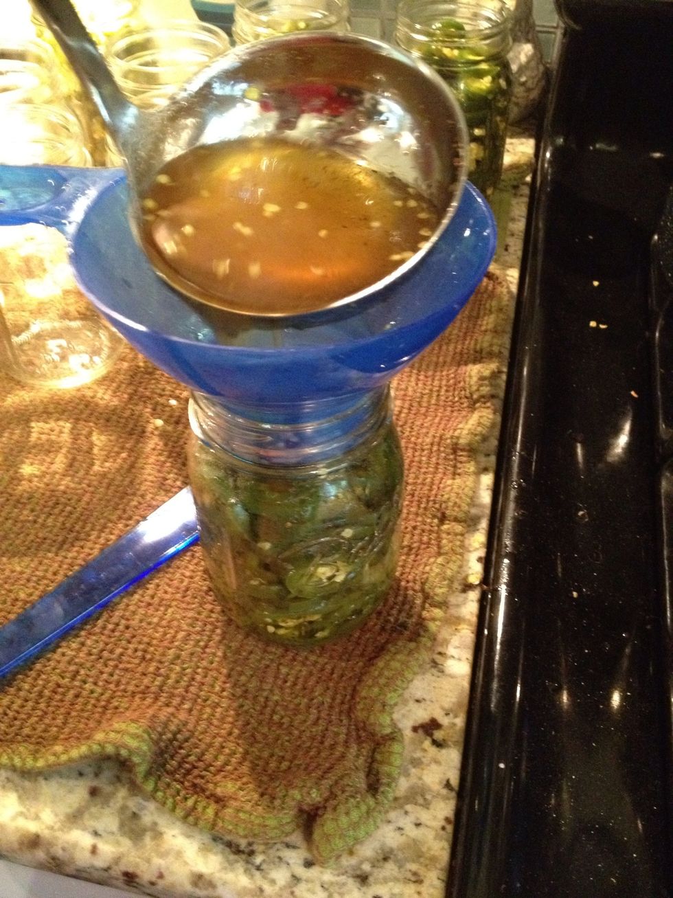 Use a ladel to pour the boiling syrup into the jars over the jalape\u00f1o slices. Fill the syrup to just below the rim of the jar.