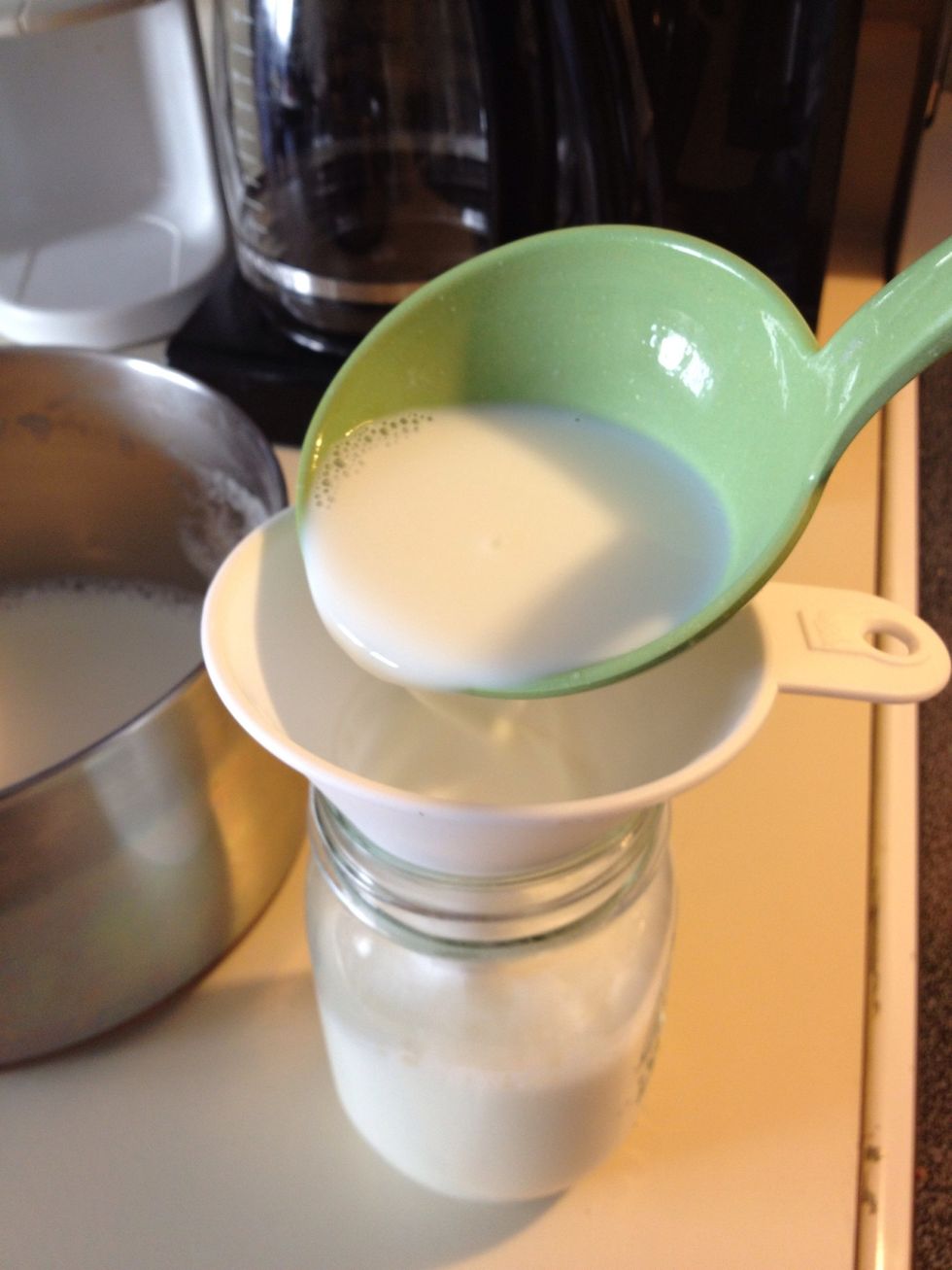 Use a ladle or a measuring cup to pour the milk-yogurt mix into the jars or containers.