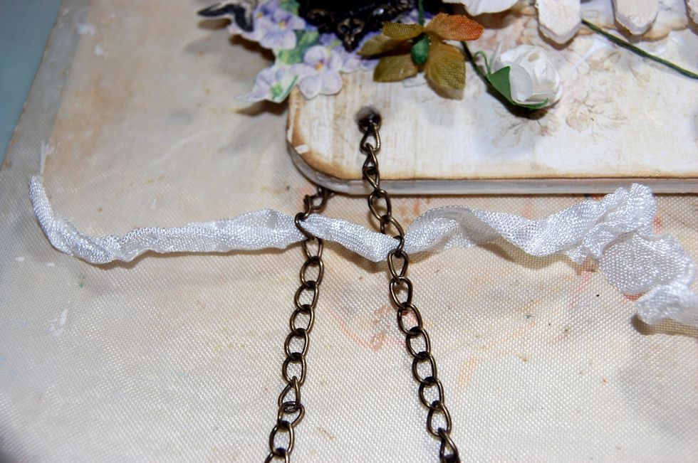 Use a length of chain to hang the plaque with. Thread the chain through the holes in the plaque. Then use a short length of seam binding ribbon passed through links in both tails of chain