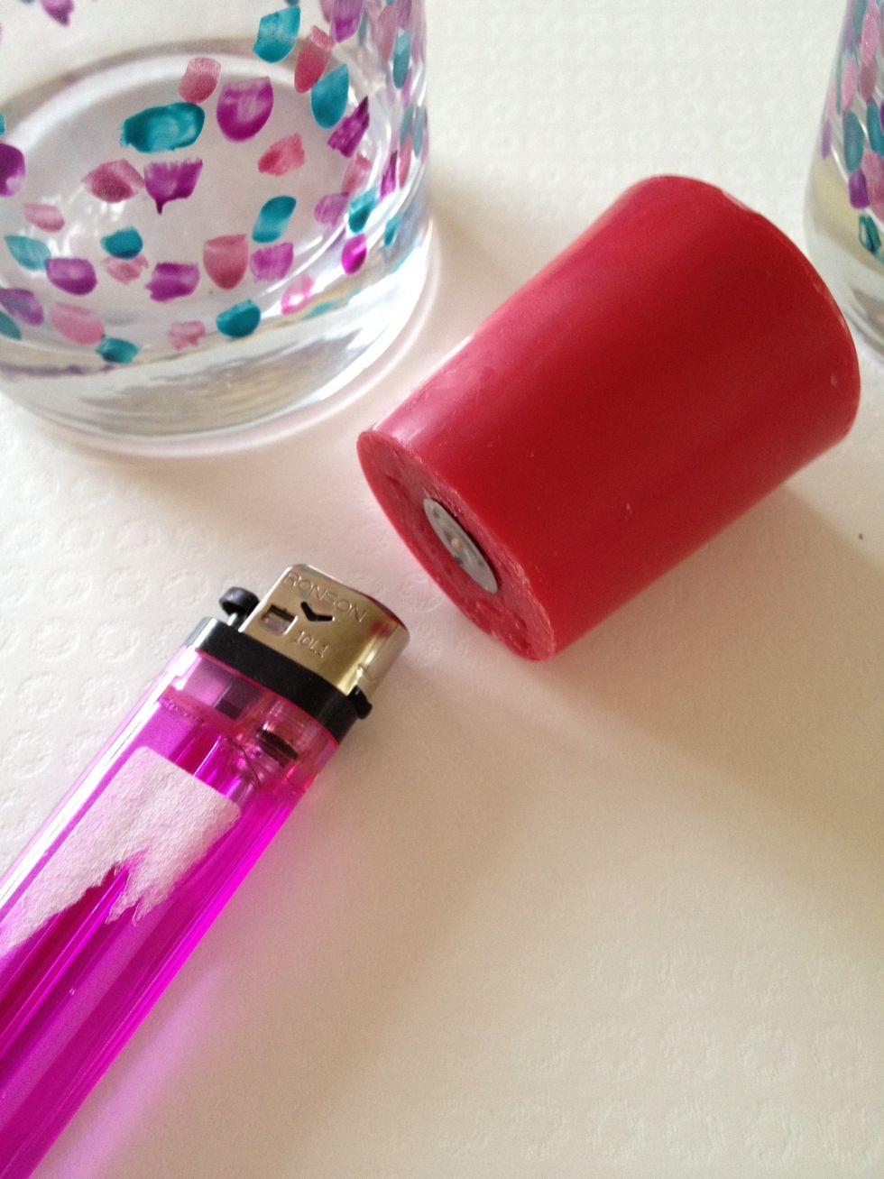 Use a lighter to slightly melt the bottom of the candle to secure it to the glass :)