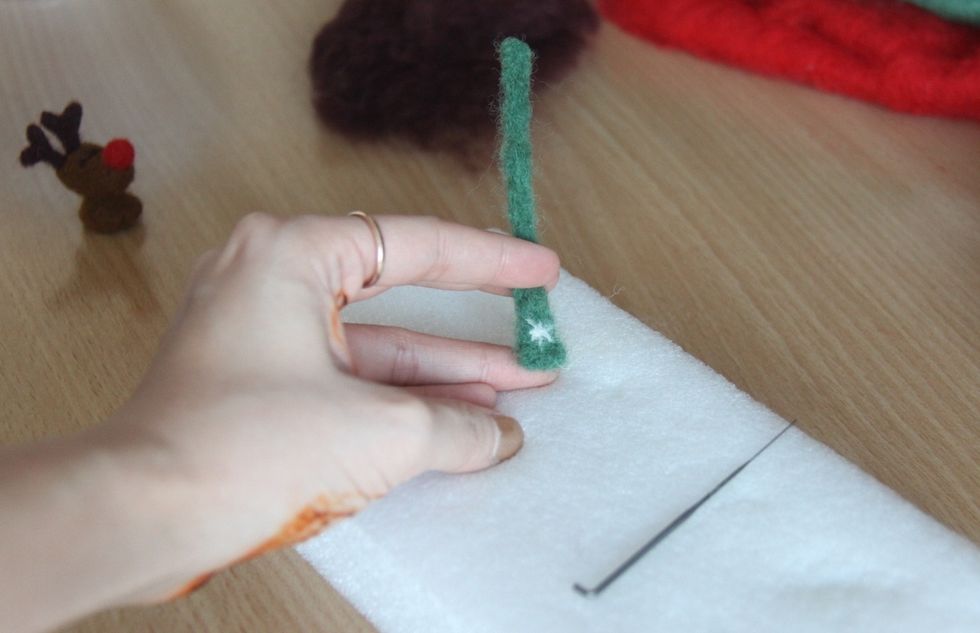 Use a little bit of white wool to decorate the scarf and then attach the scarf to the neck of Rudolf.