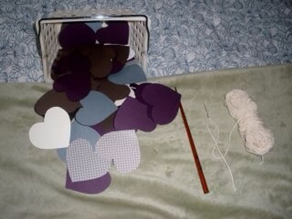 Use a long craft of knitting needle to poke two holes in the paper hearts.