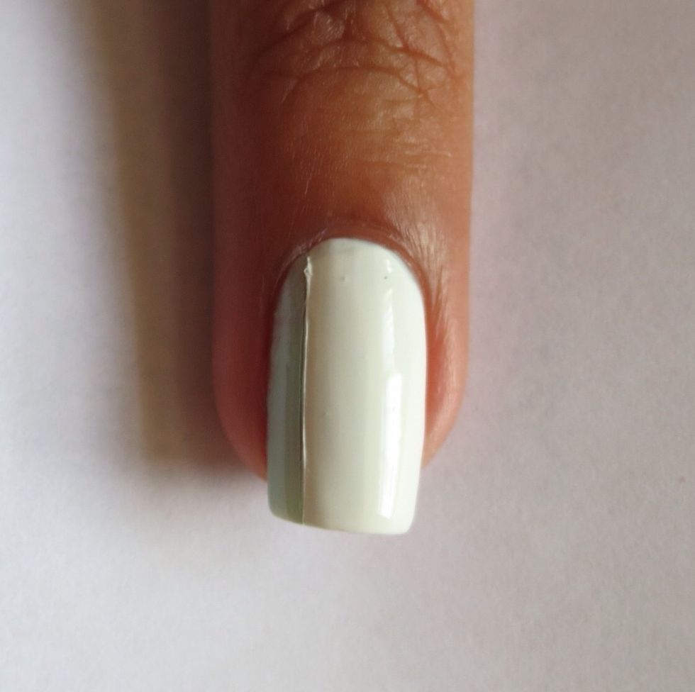 Use a nail art brush to draw a white line down the nail and fill the section in with white polish