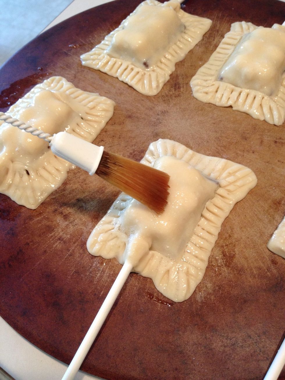 Use a pastry brush to add the egg whites to the s'mores pie pops.