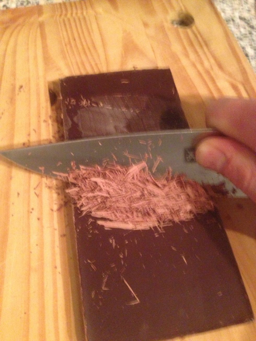 Use a sharp knife to scrape the back of the chocolate to create chocolate shaving to place on top of the cream.