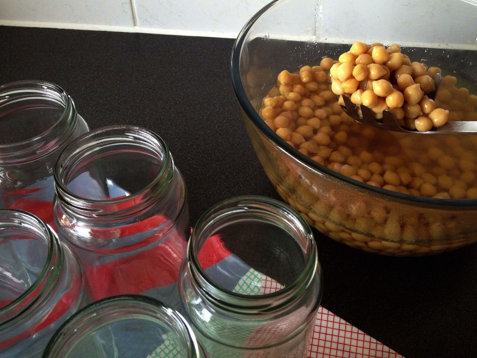 Use a slotted spoon to fill the jars with beans. Leave some space between the beans and the top of the jars.