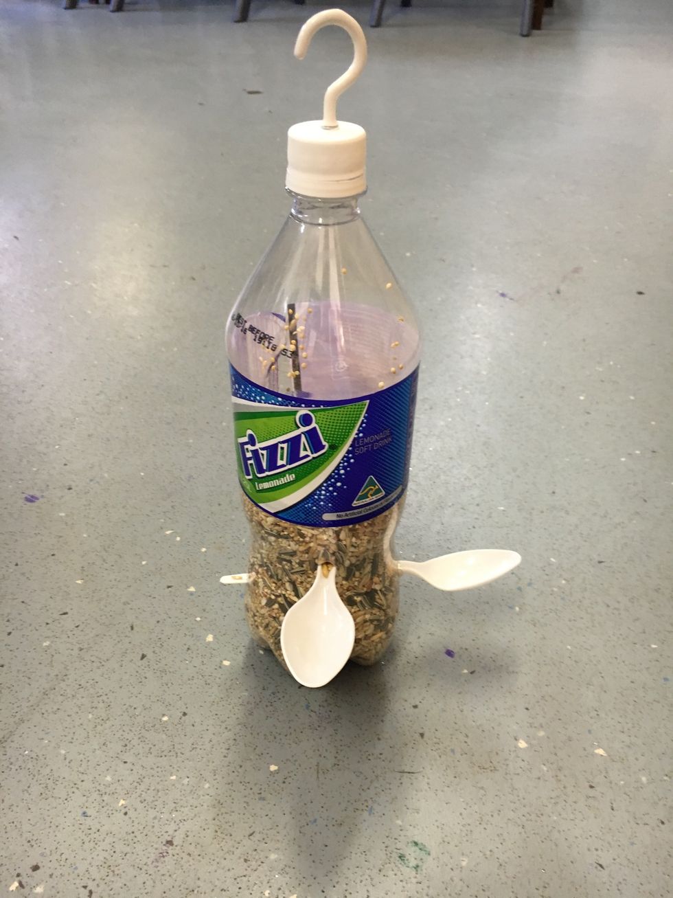 *Use a small knife, to create 3 holes approximately a quarter from the bottom of the bottle. *Place the plastic spoons through each holes (make sure the spoons stretch from one side to the other)
