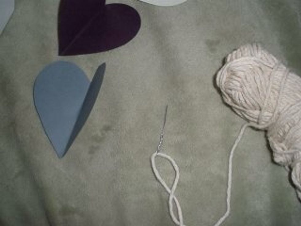 Use a smaller needle and string to thread the paper hearts. String them in the pattern you had previously designed.