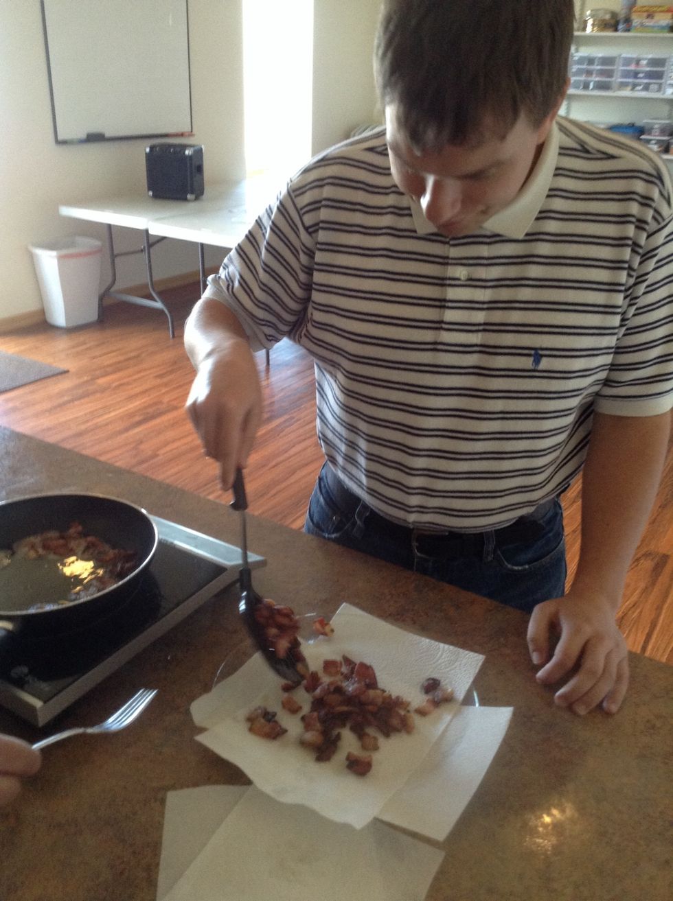Use a spatula to remove the cook bacon from the skillet to the plate with the paper towels