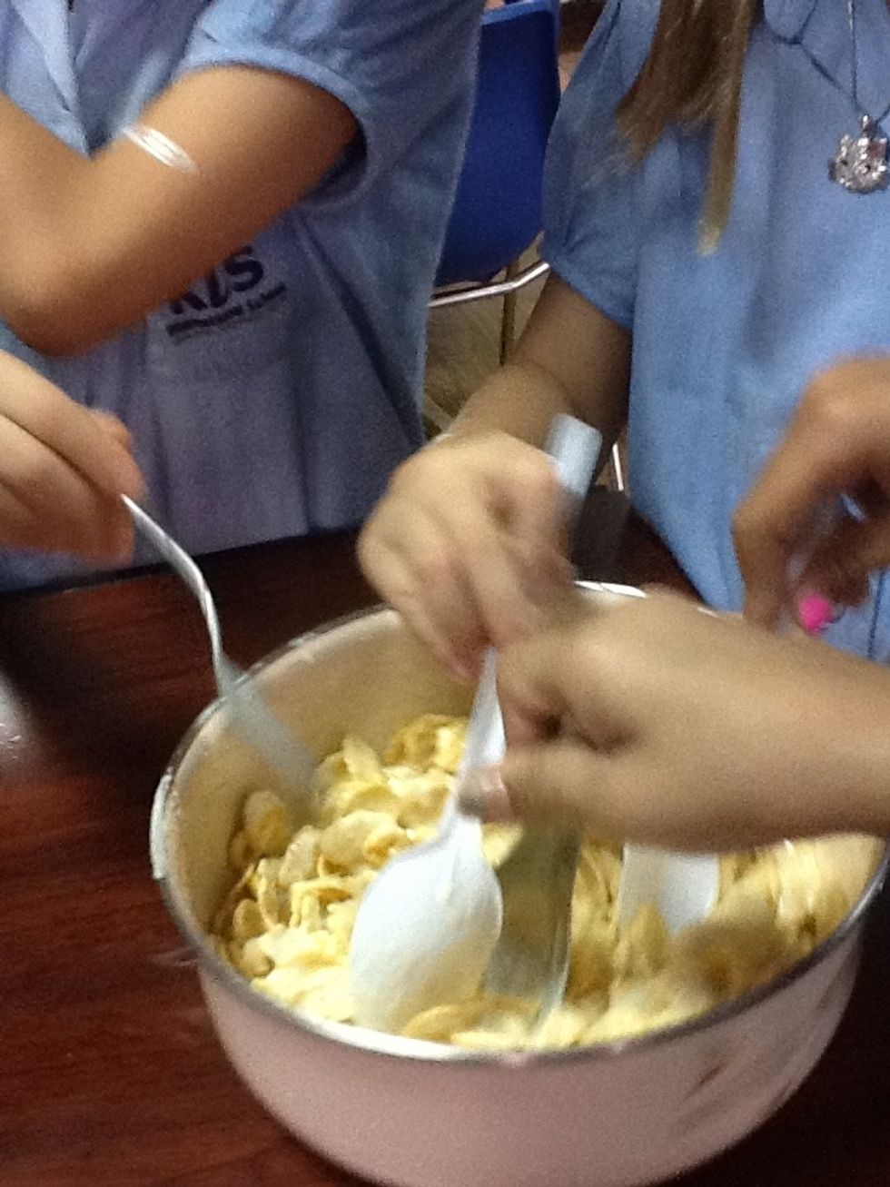 Use a spoon to stir the cornflakes into the chocolate. Make sure that you stir it quickly before it hardens.