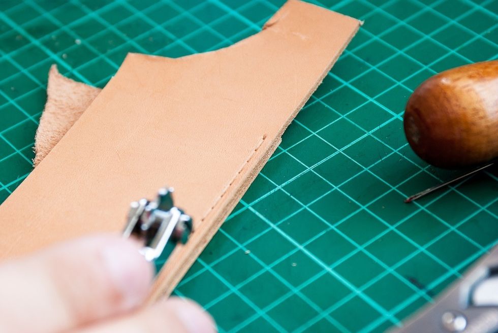 Use a stitching wheel to mark where you will make the stitches. You can also use the awl to mark the leather and measure the distances with a ruler if you don't have a stitching wheel.