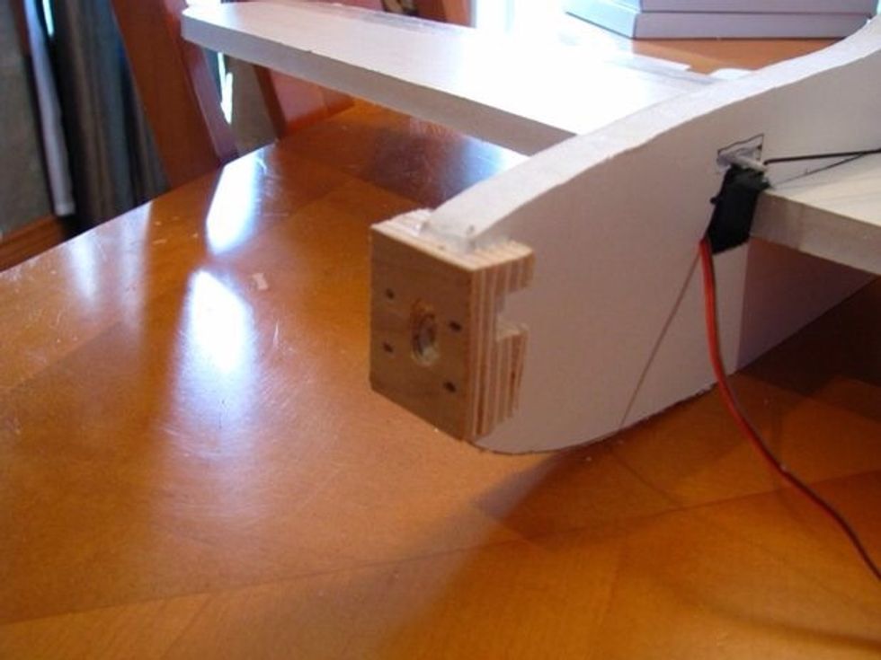 Use a table saw to cut out a slot in a block of wood to mount your motor on. Pre-drill the mounting holes in the block.