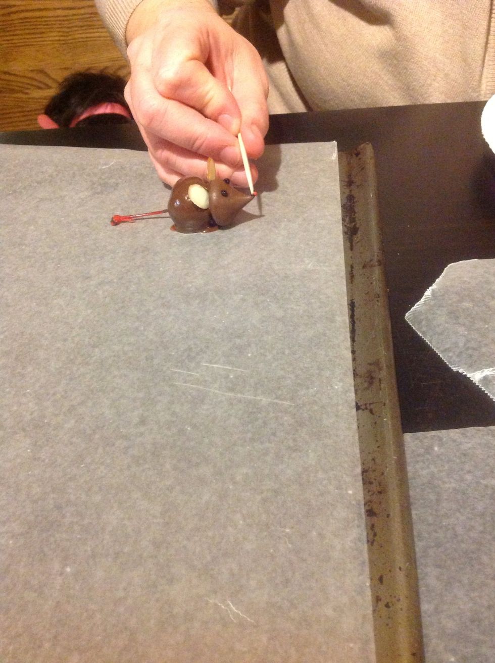 Use a toothpick with a SMALL amount of gel on the end to pick up a sprinkle and place it where you want the nose to be.