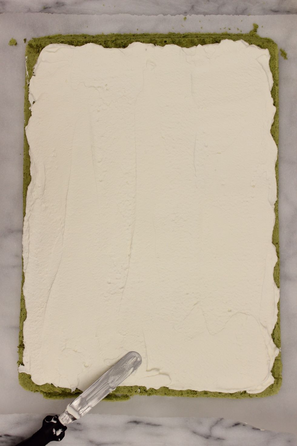 Use an off set spatula to evenly smooth out the whipped cream. Leave a 1 cm border around the cake unfrosted.