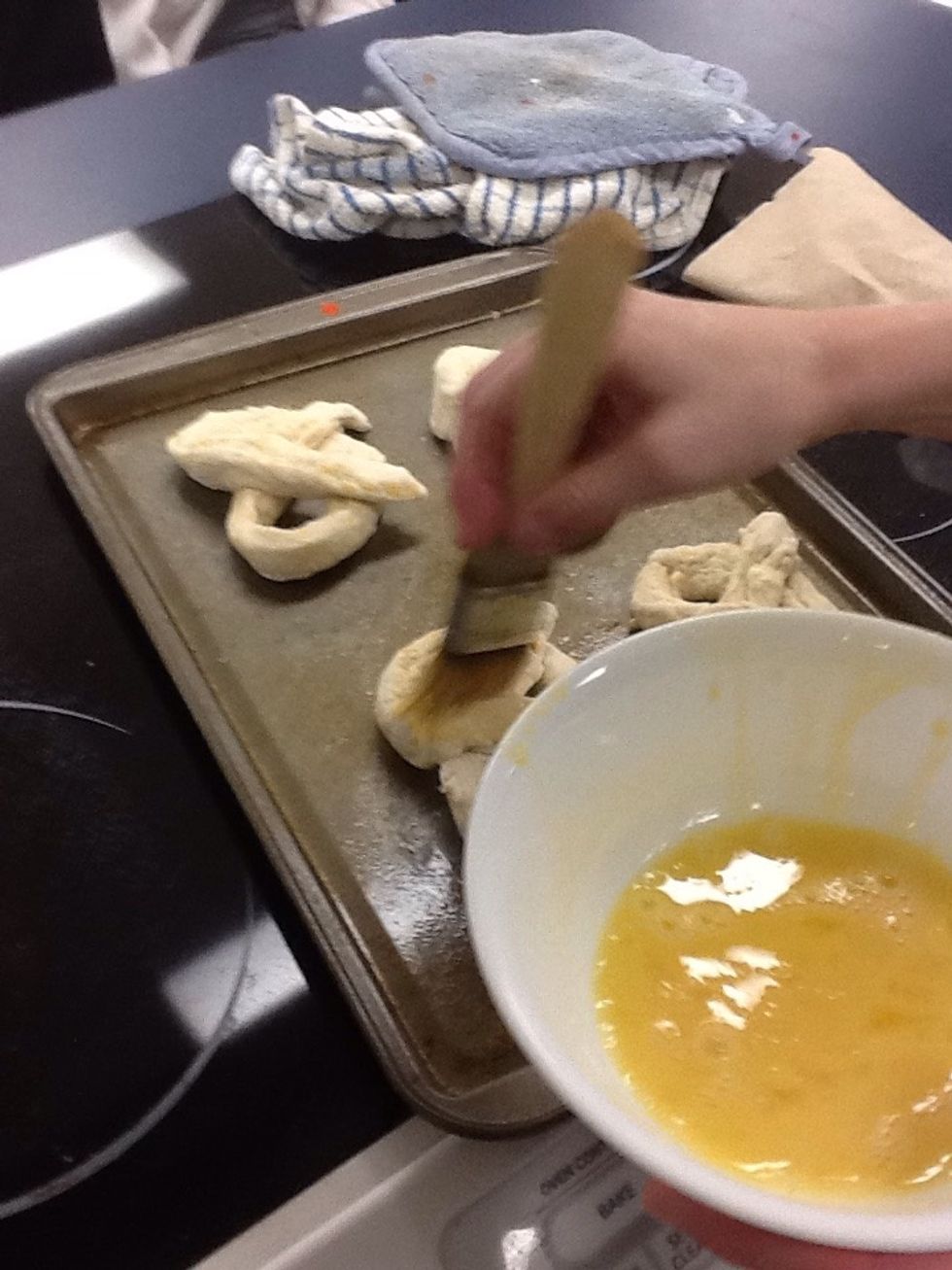Use cooking brush and lightly coat the pretzel with egg