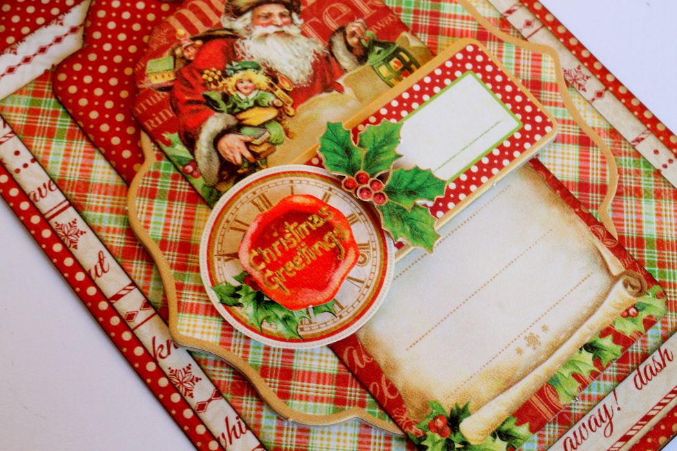Use foamtape to attach the holly leaves on the right side of the clock and the Christmas Greetings sentiment on top of it.