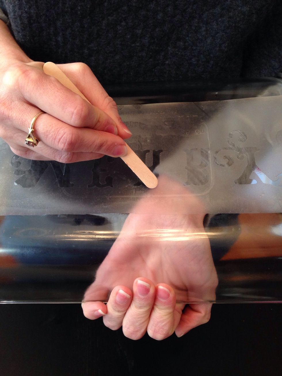 Use the craft stick to more firmly rub down all the edges so that none of the etching cream gets under the Contact paper.