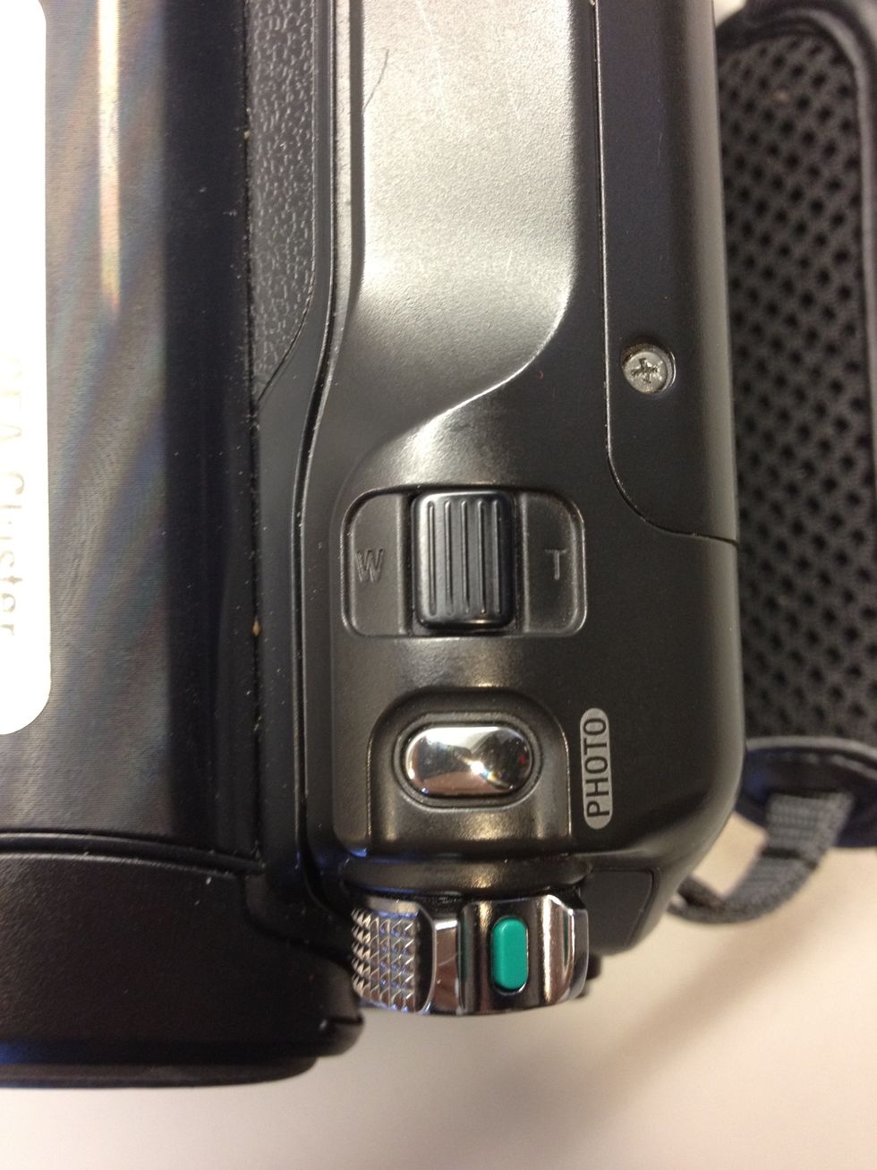 Use the lever on top to zoom. To take still photos, press the Photo button.