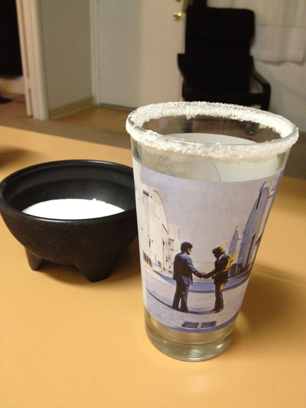 Use the lime wedge to moisten your glass, then dip into the salt to put a nice rim on it.