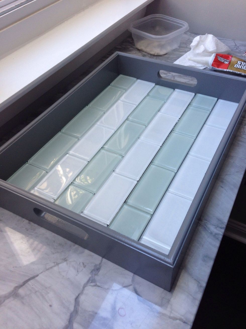 Use the liquid nails to lay down the tile in the desired pattern.
