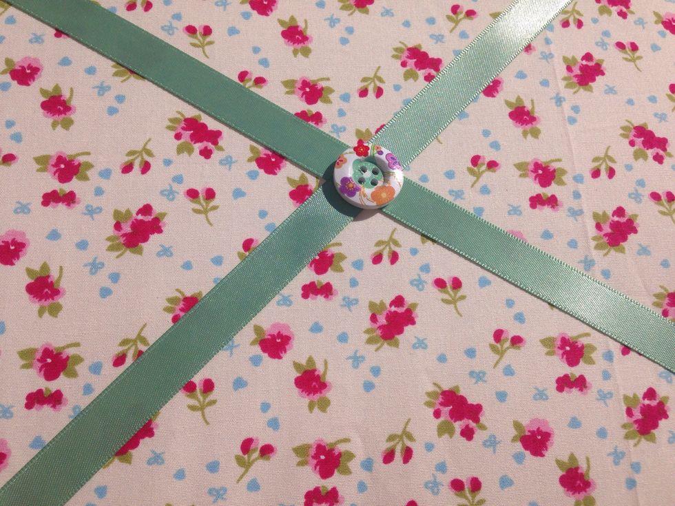 Use the needle and thread and sew each button at the point where the ribbon crosses.