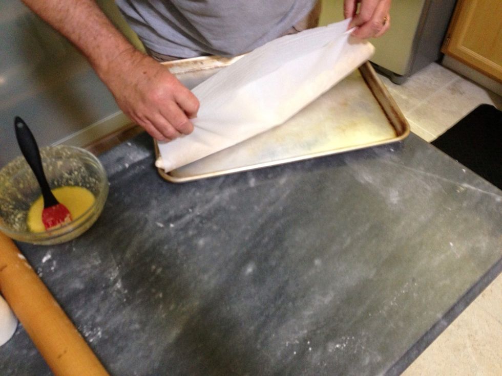 Use the parchment to lift the roll to the baking sheet.