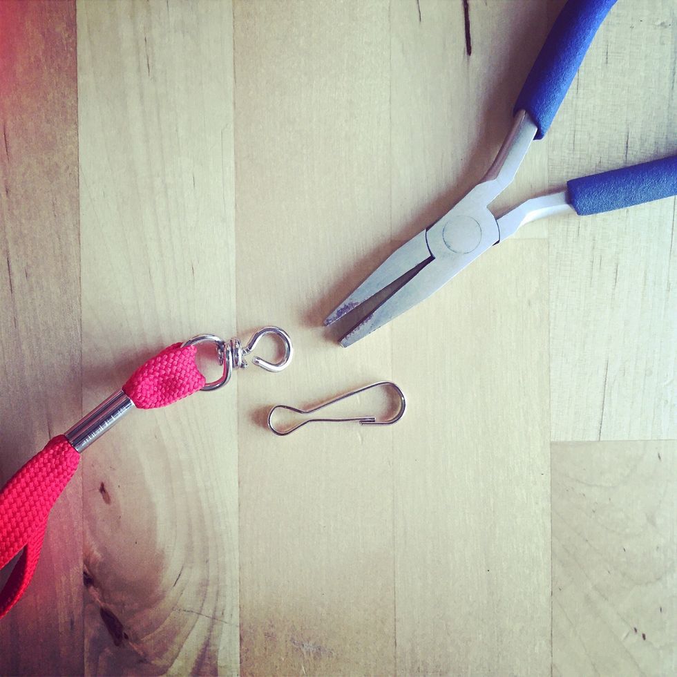 Use the pliers to remove clip from the lanyard by loosening the metal ring holding it. Keep the ring loose so you can insert it into the camera strap ring.