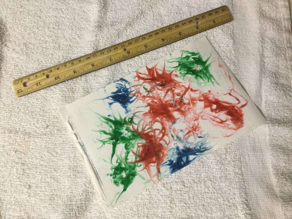 Use the ruler to scrape the excess shaving cream off the paper.