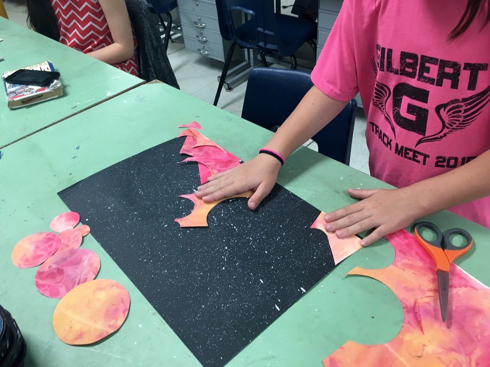 Use the scraps that were left to create a rugged landscape of a far away planet. arrange the scraps at the bottom of the space paper.