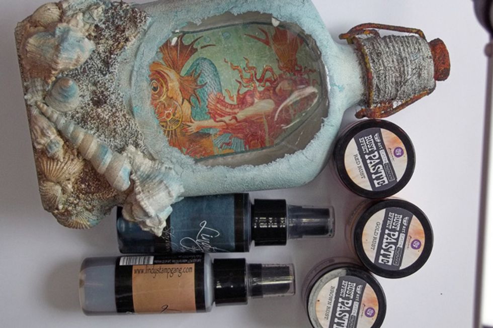 Use the Steampunk Sepia & Tainted Love Teal Starbursts and Spray the entire bottle - also splatter with the teal. Use the Rust Effect Paste on the cap and the metal latch elements of the lid.