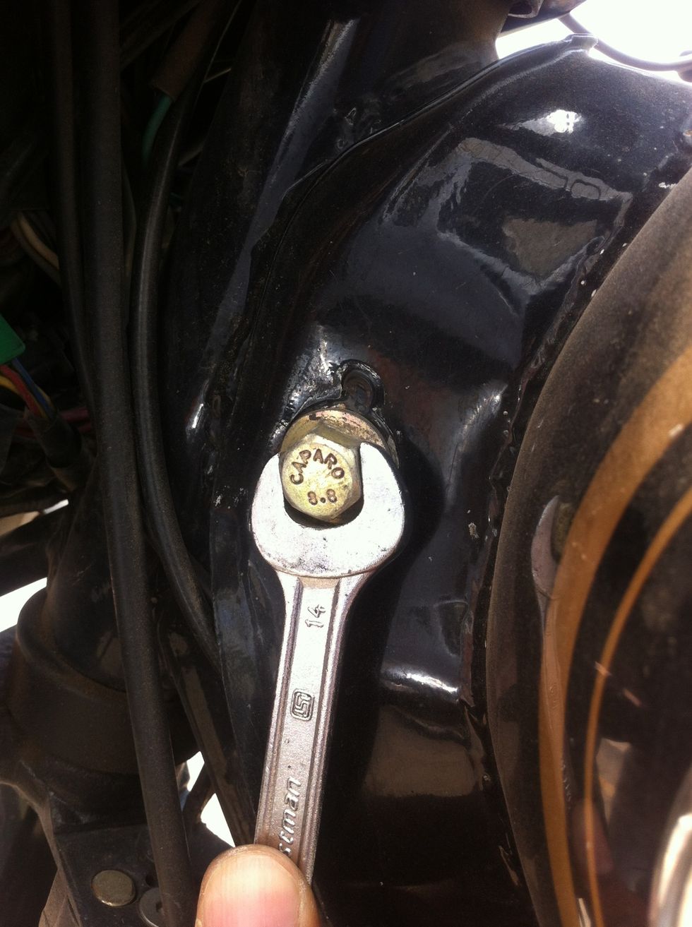 Use two 14mm spanners to remove the nut and bolt. You would need to to hold on one side and loosen on the other side. If you are super careful about your paint job, cover the body with cloth.