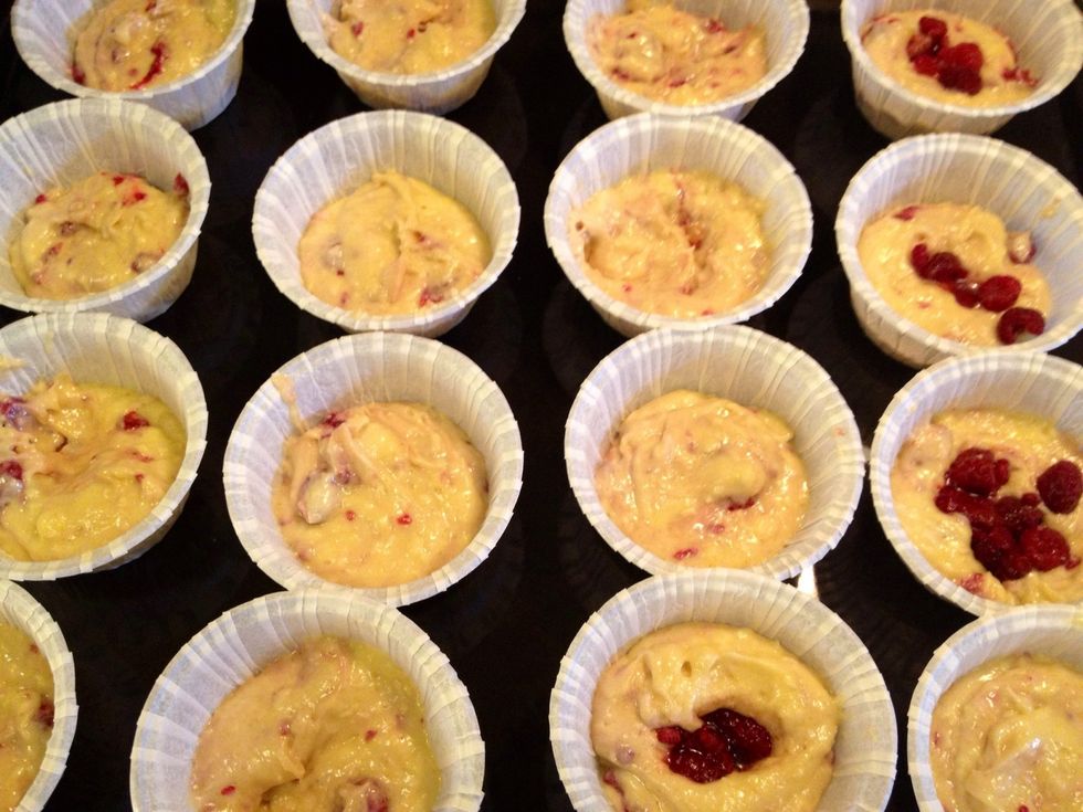 Use two spoons to divide the batter in the muffin molds. I added some extra raspberries and now they're ready to go in the oven!