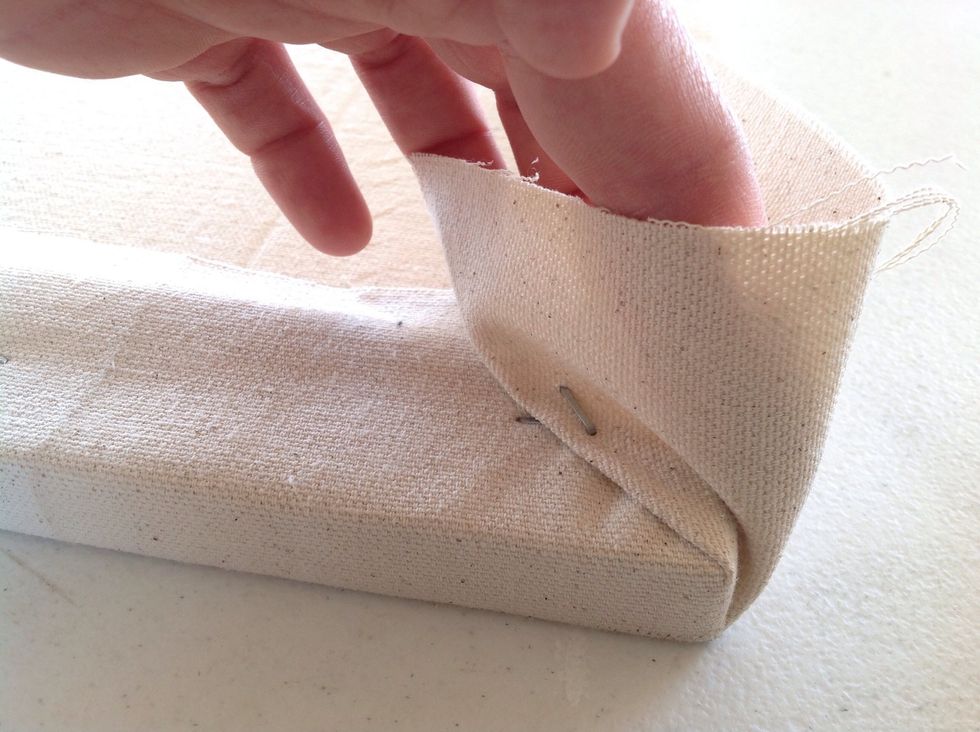 Use your finger to fold the remaining canvas down creating a crease at the very corner on the frame. Then staple that down.