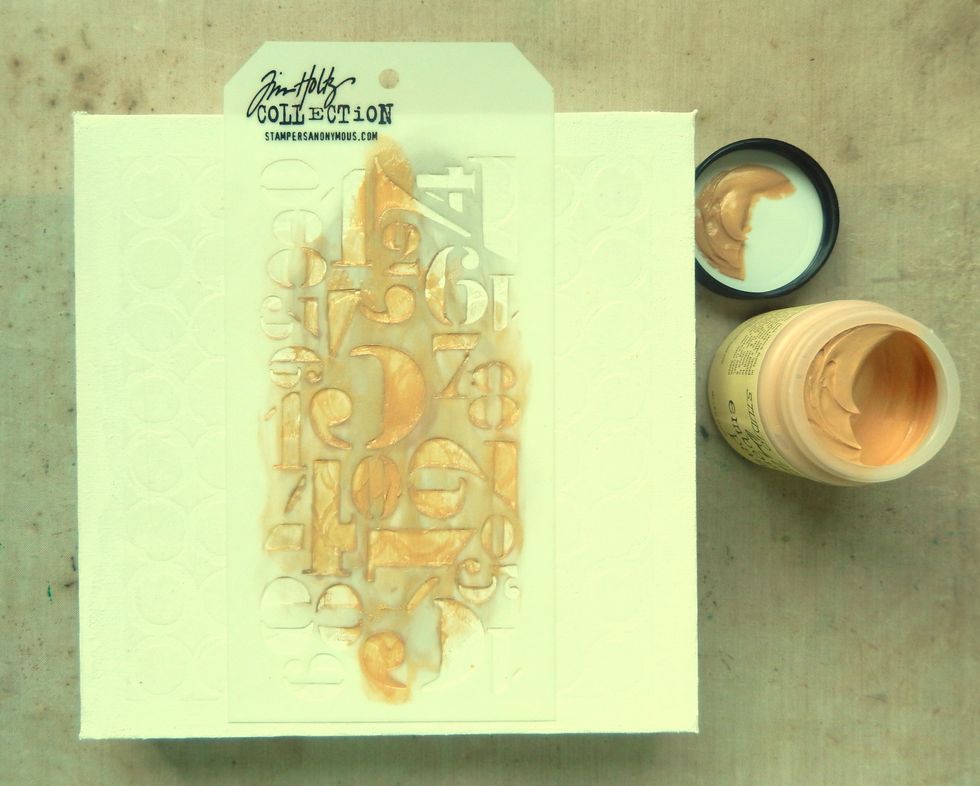 Use your finger to rub a little Gold Embossing Paste through the Numeric Layering Stencil over some of the previously stencilled areas. Allow the paste to dry.