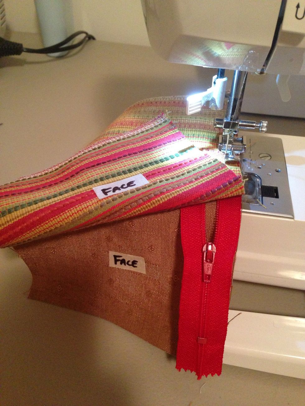 Use zipper foot to sew & move zipper head away from needle.  Make sure needle is down into fabric when zipper foot is released to move zipper head away.
