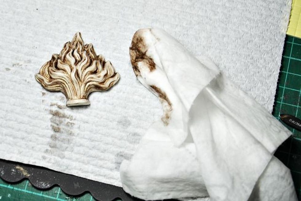 Using a baby wipe lightly rub away color from the raised parts of the flaming heart pieces. This will help define their amazing details.