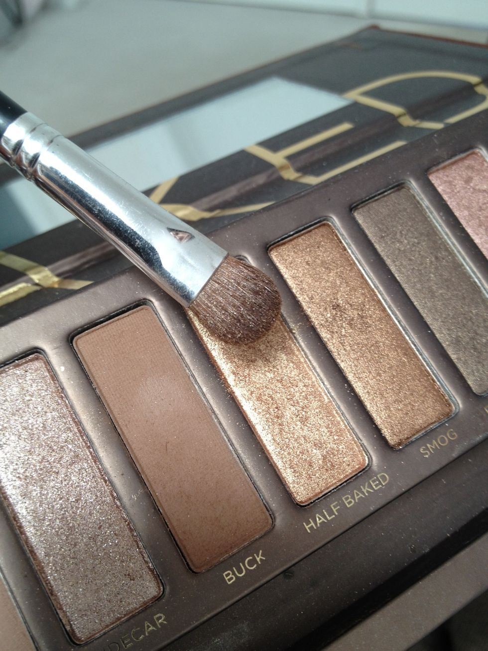 Using a c-shaped eyeshadow brush, take a bit of the golden bronze color such as "Half-baked".