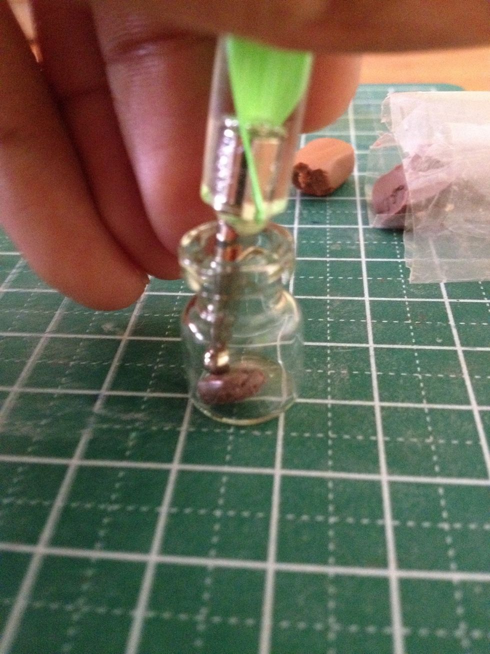 Using a dotting tool, flatten the brown piece to the bottom of the glass jar. However, make sure you don't use too much force or else it'll lose its texture.