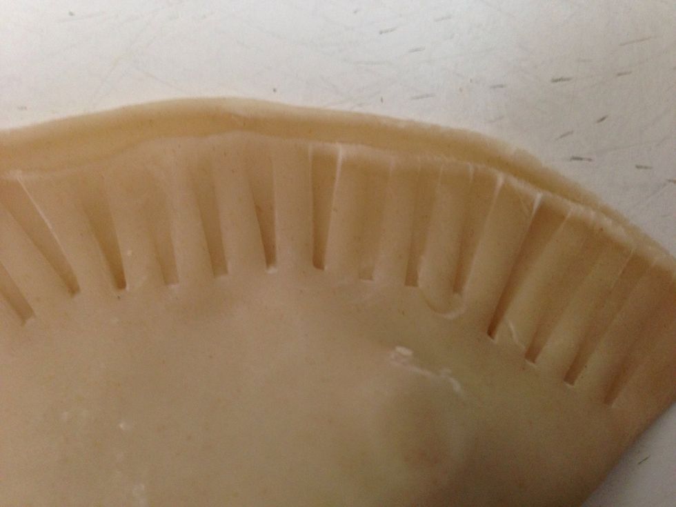 Using a fork, make small indentations along the outer rim of the empanadas.