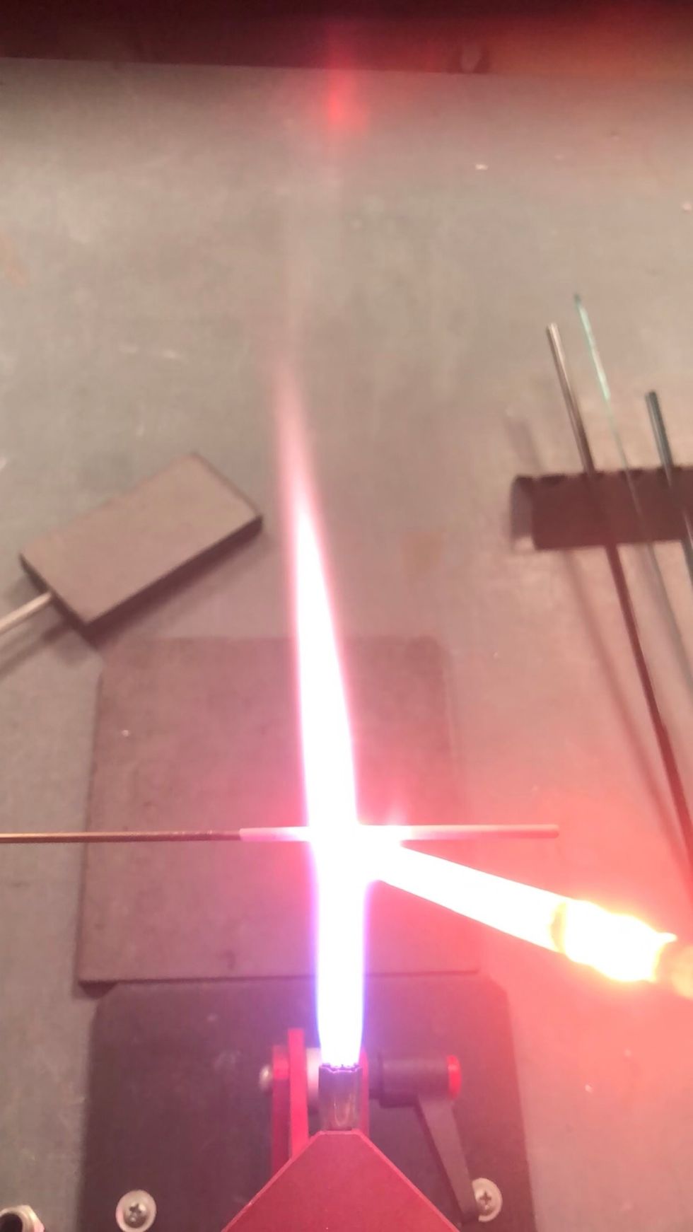 Using a hot flame, lay down a layer of Zephyr where the bead will be. Use enough heat so the glass flows onto the mandrel easily.