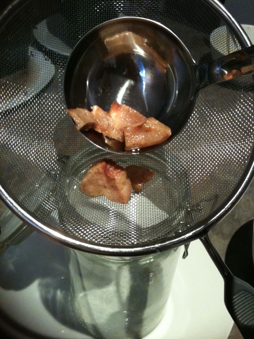 Using a ladle, pour the rendered lard through the seive into the jar, placing the leftover rind into a separate bowl.