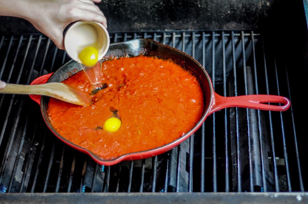 Using a large spoon, make a shallow well in the tomato sauce, and crack or pour an egg in the divot. Repeat for remaining eggs. Close the grill lid.