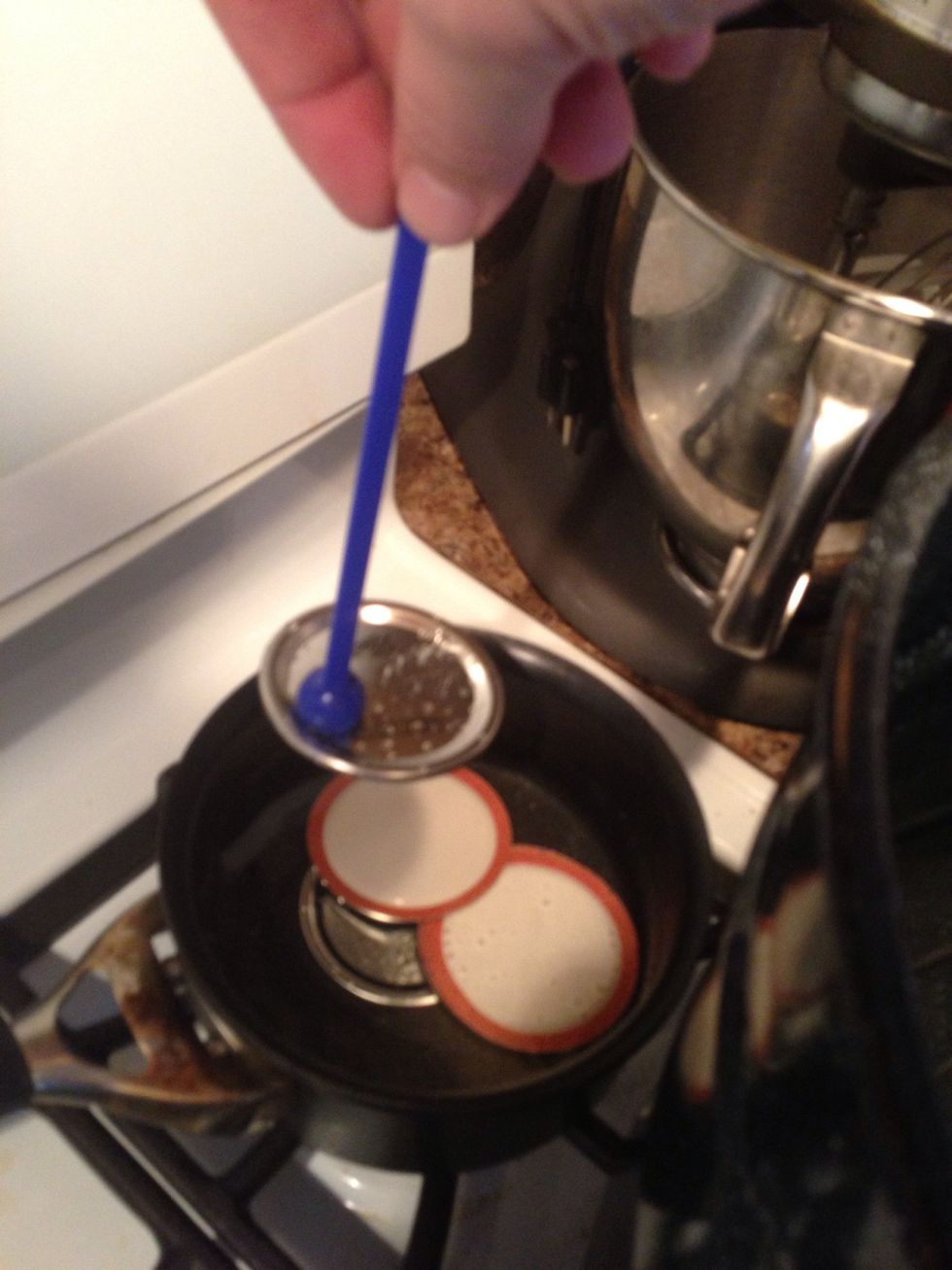 Using a lid lifter (a magnet on a stick) remove the lids and place them on the jars.