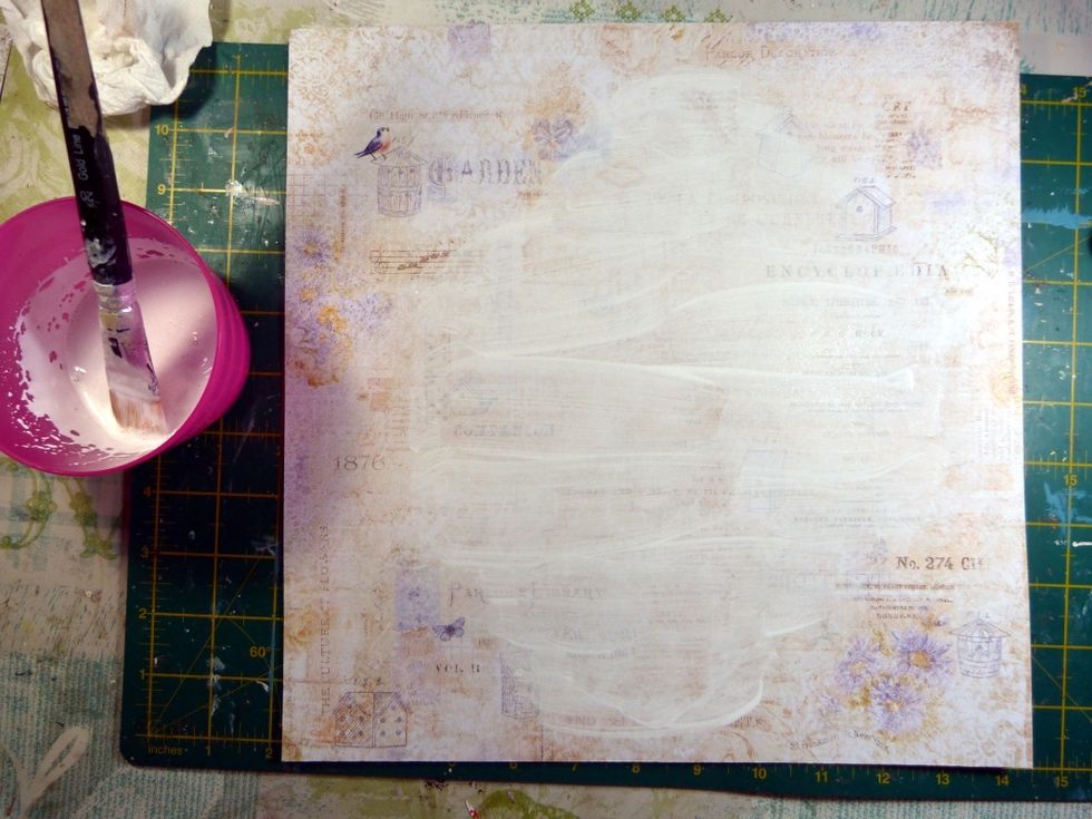 Using a mix of gesso and water, brush over the central area of the background paper where we are going to add our layered feature. Dry.