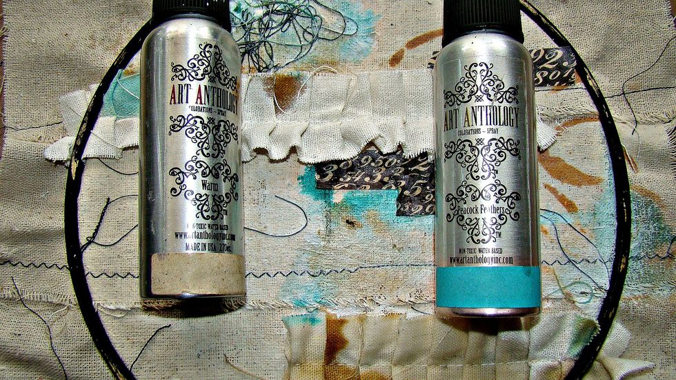 Using a paint brush I dribbled my sprays on my muslin backing. Because this was prepped with gesso the sprays flow nicely, Spritz water to allow movement and heat set. I then added some washi tape.