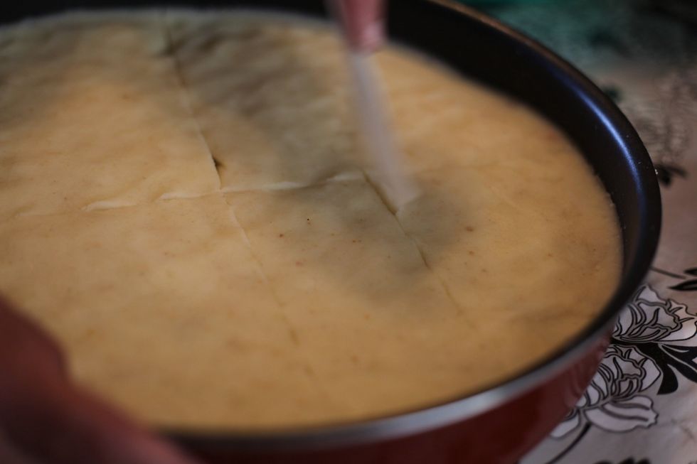 Using a plastic knife or spatula cut in to the tray into squares. Why? Coz we love butter so much we're going to put it on top too. So we want the flavour to sink through.
